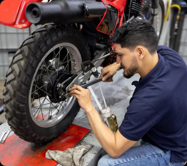 Mechanic servicing a motorcycle in an independent aftermarket workshop.